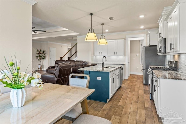 1412 Areca Palm Dr, Gulf Breeze, FL 32563 - kitchen with appliances with stainless steel finishes, open floor plan, ornamental molding, white cabinets, and wood finished floors