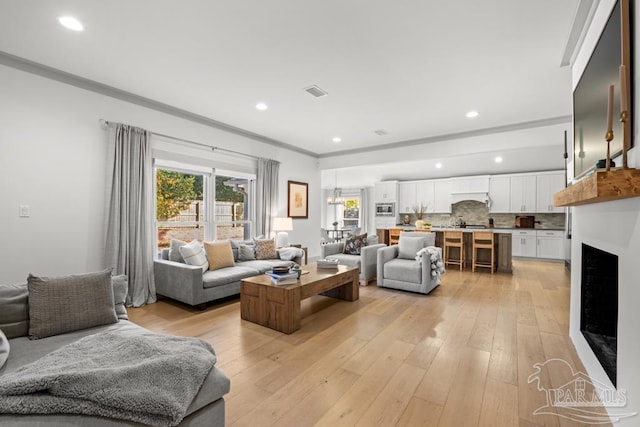 living room featuring light wood-type flooring and crown molding