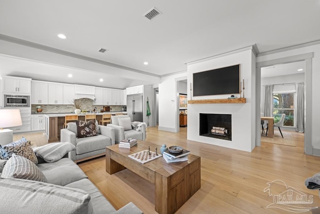 living room featuring light hardwood / wood-style flooring and crown molding