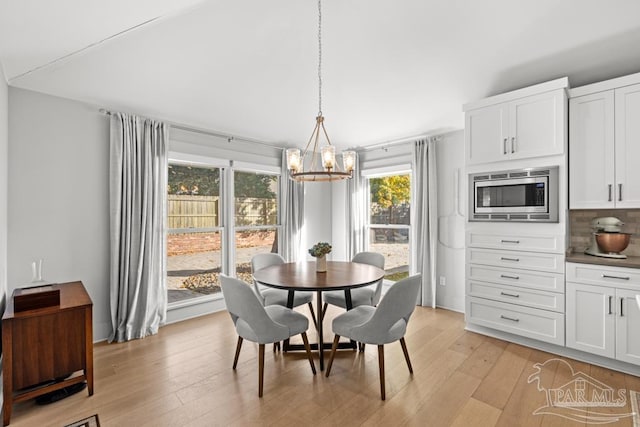 dining space with light hardwood / wood-style floors and an inviting chandelier