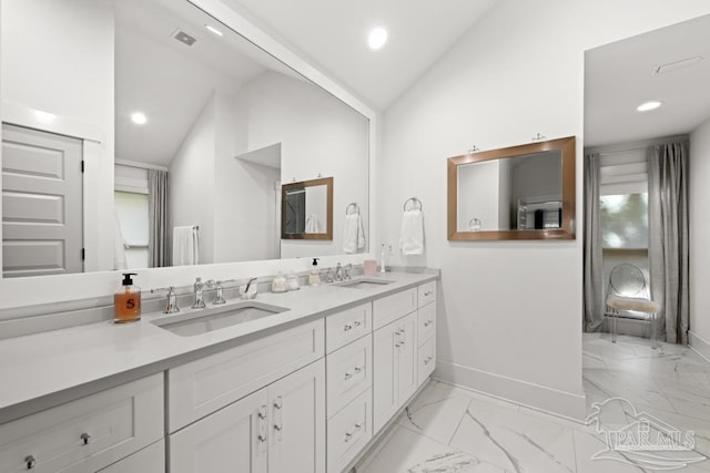 bathroom featuring a healthy amount of sunlight, vanity, and lofted ceiling