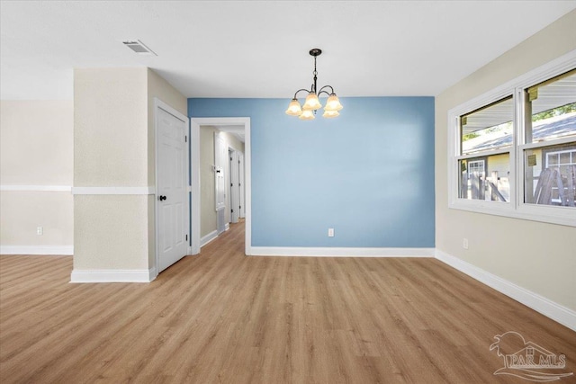 empty room with a chandelier and light wood-type flooring