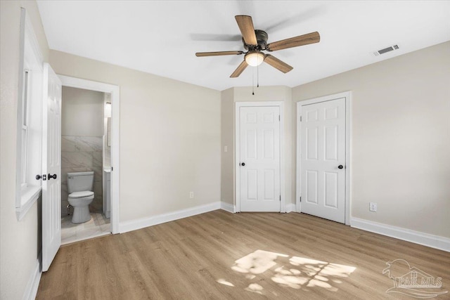 unfurnished bedroom featuring ceiling fan, light wood-type flooring, and ensuite bath