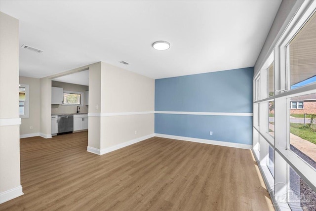 spare room with plenty of natural light, sink, and light hardwood / wood-style floors