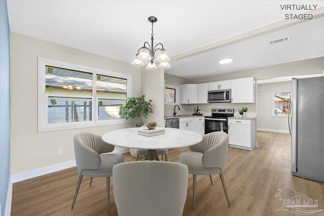 dining space with sink, light hardwood / wood-style flooring, and a chandelier