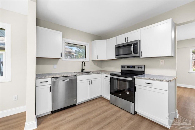 kitchen featuring stainless steel appliances, sink, a wealth of natural light, and white cabinets