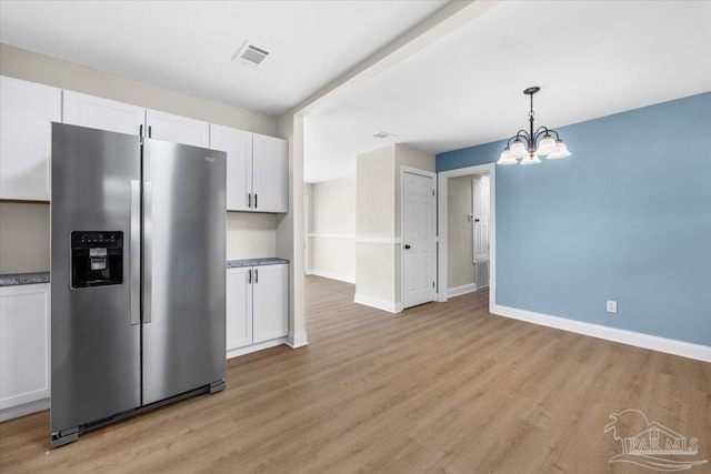 kitchen featuring stainless steel fridge, white cabinets, and light wood-type flooring