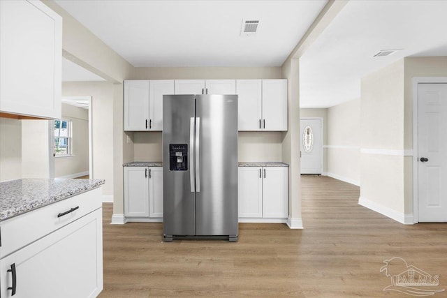 kitchen featuring stainless steel fridge with ice dispenser, light hardwood / wood-style flooring, and white cabinets