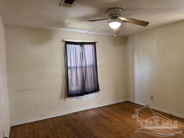 spare room featuring visible vents, ceiling fan, a textured ceiling, and wood finished floors