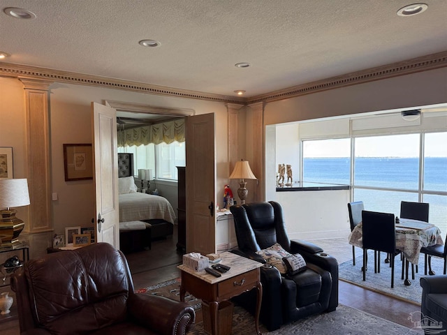 living room with a water view, wood-type flooring, and a textured ceiling