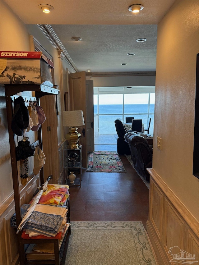 hallway featuring a water view, crown molding, and a textured ceiling