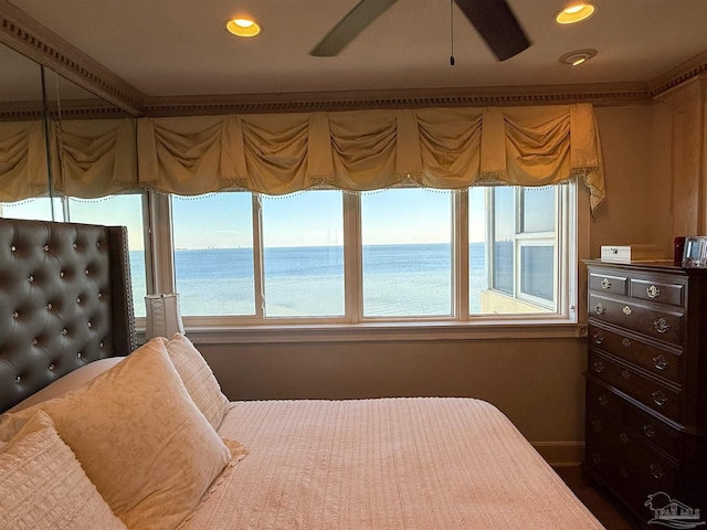 bedroom with ceiling fan and a water view