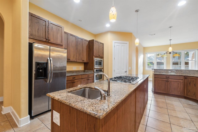 kitchen with a center island with sink, sink, appliances with stainless steel finishes, and decorative light fixtures