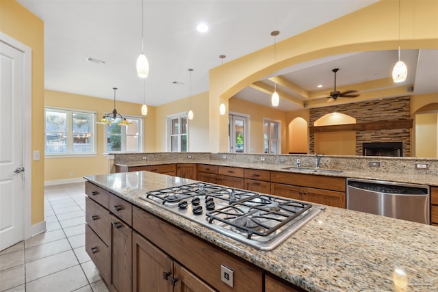 kitchen with decorative light fixtures, stainless steel appliances, sink, and light stone counters