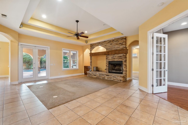 unfurnished living room featuring french doors, light tile patterned flooring, a fireplace, and a raised ceiling