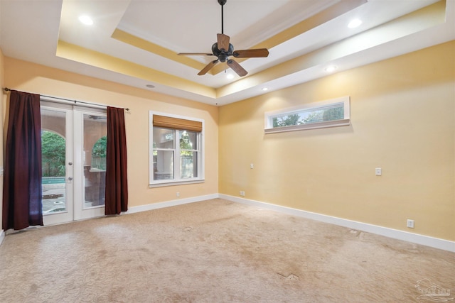 carpeted empty room featuring french doors, ornamental molding, a tray ceiling, and ceiling fan