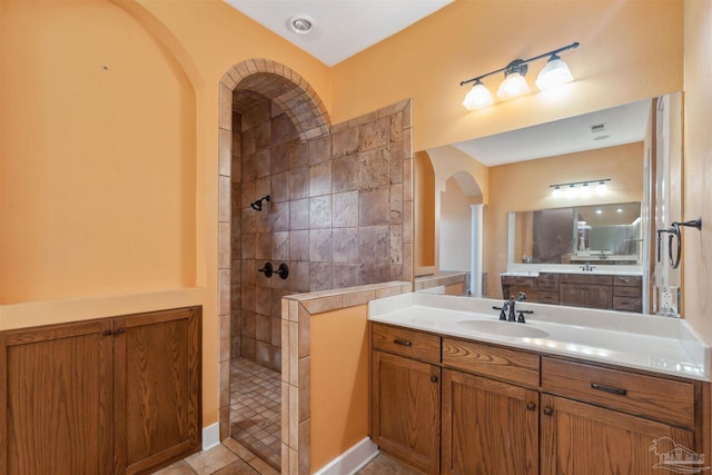 bathroom with a tile shower, vanity, and tile patterned flooring