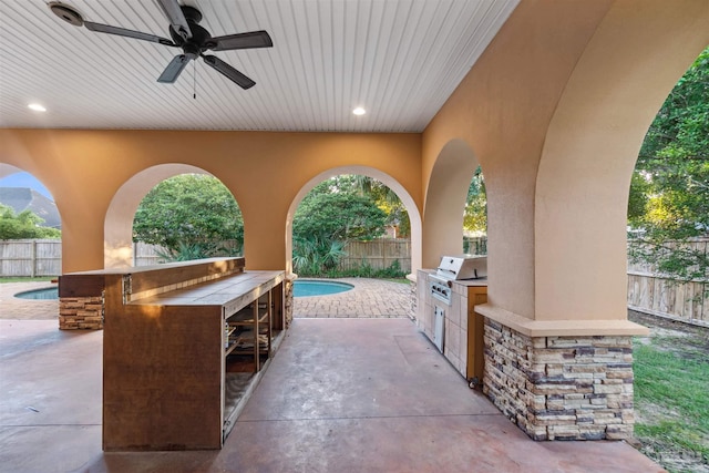 view of patio featuring an outdoor kitchen, area for grilling, a fenced in pool, and ceiling fan