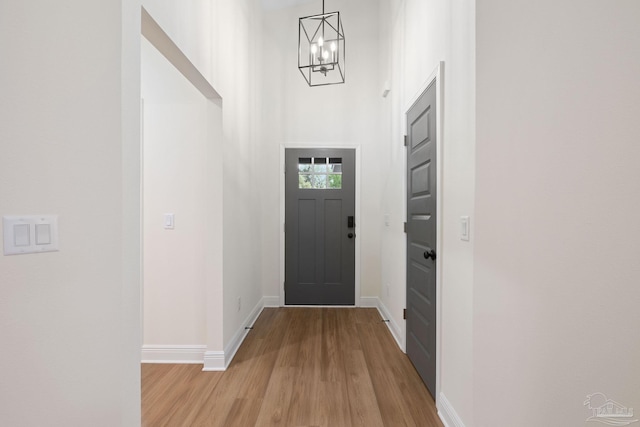foyer featuring baseboards, a chandelier, and light wood-style floors