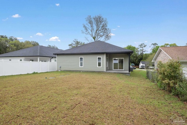 rear view of house featuring a yard and fence