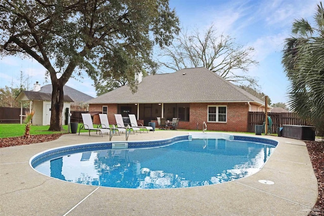 view of swimming pool with a patio area, fence, a fenced in pool, and an outbuilding