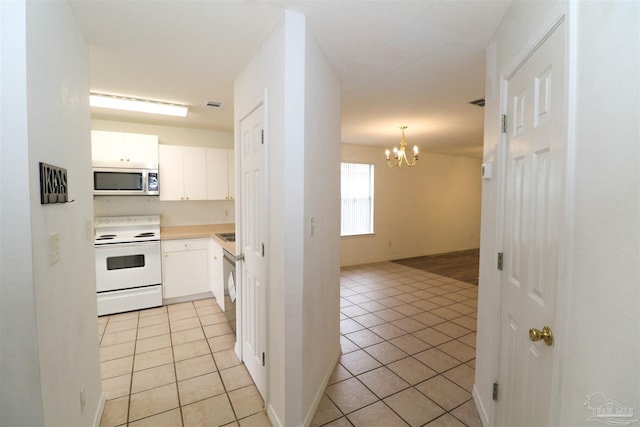 kitchen with white cabinets, hanging light fixtures, light tile patterned floors, electric range, and a chandelier