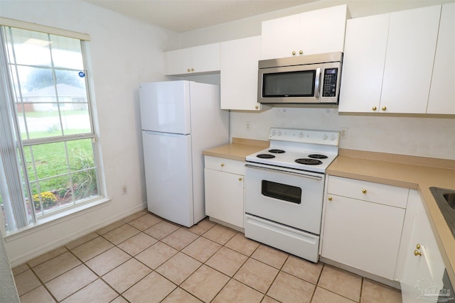 kitchen with light tile patterned floors, white appliances, and white cabinetry