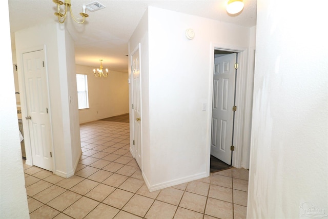 hallway featuring an inviting chandelier and light tile patterned flooring