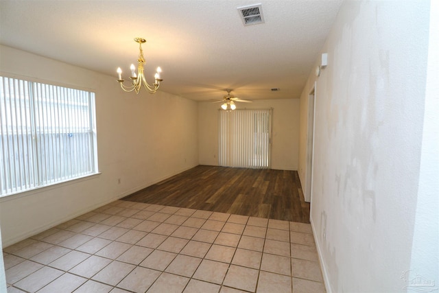 unfurnished room with ceiling fan with notable chandelier and light wood-type flooring