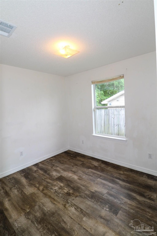 empty room featuring dark wood-type flooring and a textured ceiling