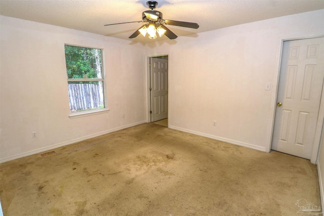 carpeted spare room with a textured ceiling and ceiling fan