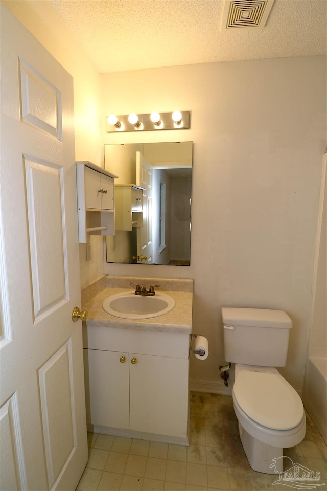 bathroom with toilet, a textured ceiling, and vanity