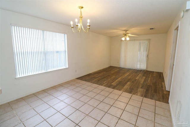 unfurnished room featuring ceiling fan with notable chandelier and light hardwood / wood-style flooring