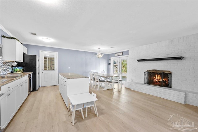 931 Pocahontas Dr, Ft Walton Beach, FL 32547 - kitchen with white cabinets, a center island, decorative light fixtures, and a brick fireplace
