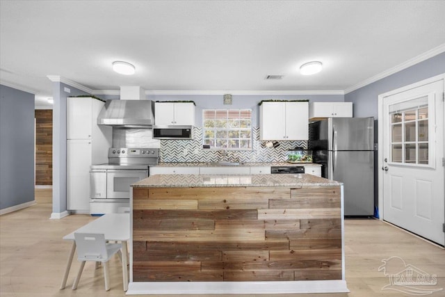 931 Pocahontas Dr, Ft Walton Beach, FL 32547 - kitchen with light stone countertops, white cabinetry, stainless steel appliances, and wall chimney range hood