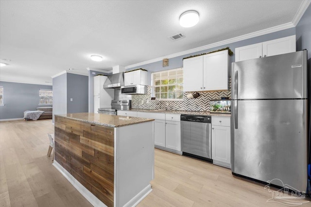 931 Pocahontas Dr, Ft Walton Beach, FL 32547 - kitchen featuring white cabinets, light stone counters, wall chimney range hood, and appliances with stainless steel finishes