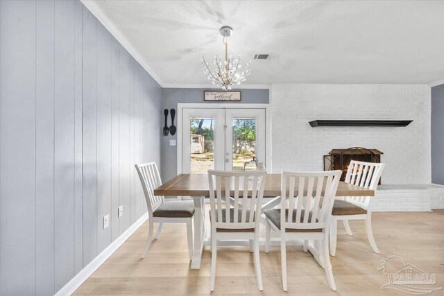 931 Pocahontas Dr, Ft Walton Beach, FL 32547 - dining room with french doors, an inviting chandelier, crown molding, light hardwood / wood-style floors, and wooden walls