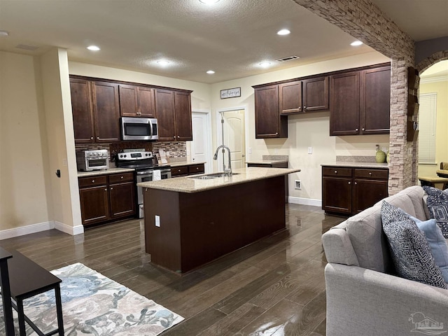 kitchen featuring a center island with sink, stainless steel appliances, light countertops, visible vents, and a sink