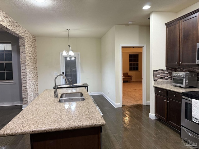 kitchen with dark brown cabinetry, tasteful backsplash, an island with sink, appliances with stainless steel finishes, and a sink