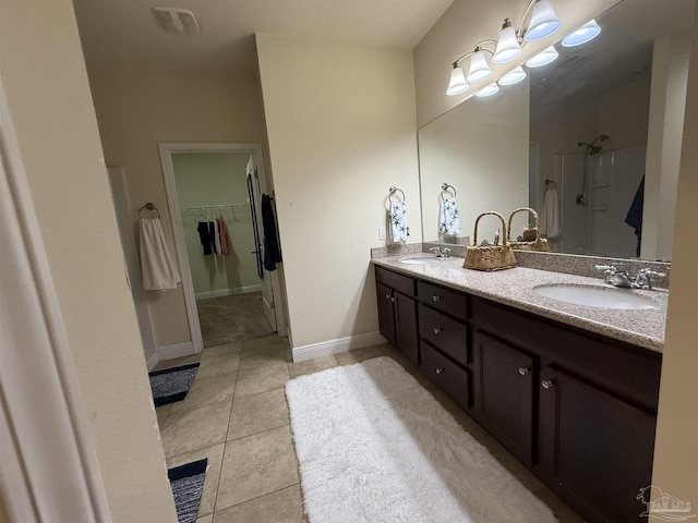 full bath with double vanity, a sink, a spacious closet, and tile patterned floors