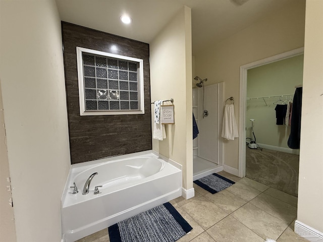 bathroom with a stall shower, baseboards, a garden tub, tile patterned flooring, and a walk in closet