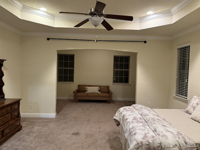 bedroom featuring light carpet, a tray ceiling, ornamental molding, and baseboards