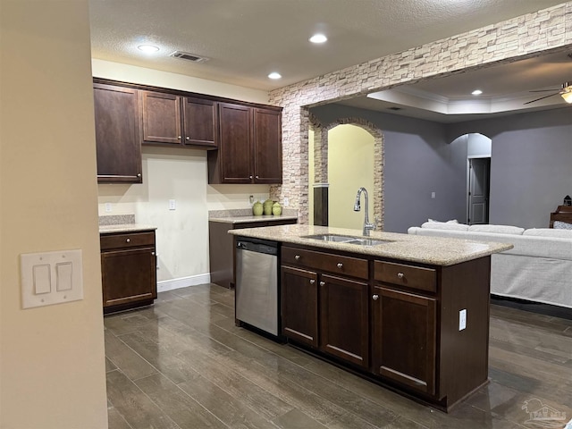 kitchen with arched walkways, open floor plan, light countertops, stainless steel dishwasher, and a sink