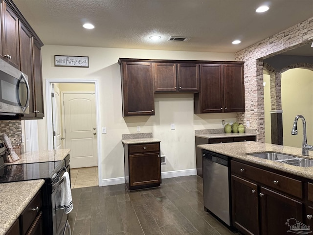 kitchen featuring dark brown cabinets, visible vents, stainless steel appliances, and a sink