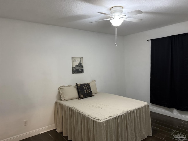 bedroom with a textured ceiling, dark wood-style flooring, and baseboards