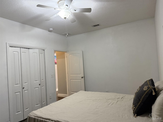 bedroom featuring a ceiling fan, a textured ceiling, visible vents, and a closet