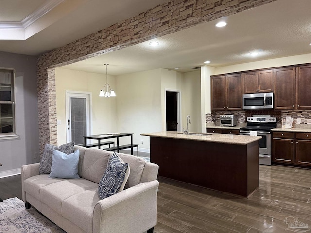 kitchen featuring a center island with sink, decorative light fixtures, stainless steel appliances, light countertops, and a sink