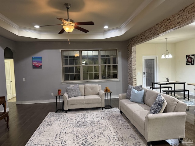 living room with ornamental molding, arched walkways, a raised ceiling, and dark wood-style flooring