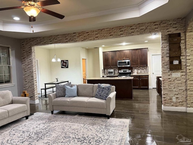 living room with baseboards, a raised ceiling, ceiling fan, ornamental molding, and recessed lighting