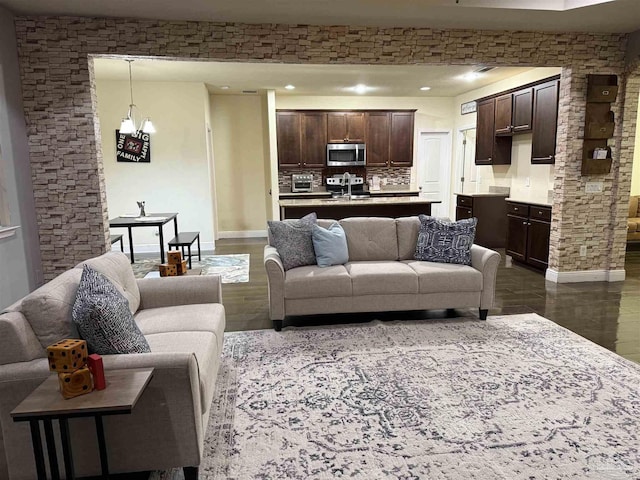 living room with dark wood-style flooring, an inviting chandelier, and baseboards